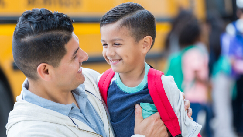 father holding son by the school bus